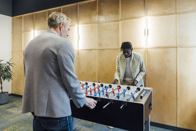 Multiracial businessmen playing foosball in office