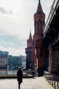 Rear view of woman standing outside building against sky