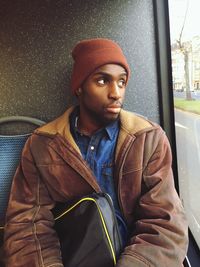 Young man looking through window while sitting in bus