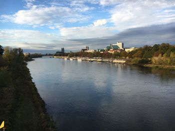 Scenic view of river by buildings against sky