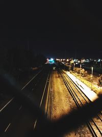 Illuminated railroad tracks in city at night