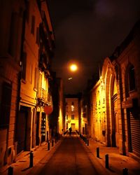 Empty road along buildings at night