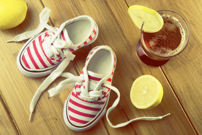High angle view of child shoes by tea cup with lemon on table