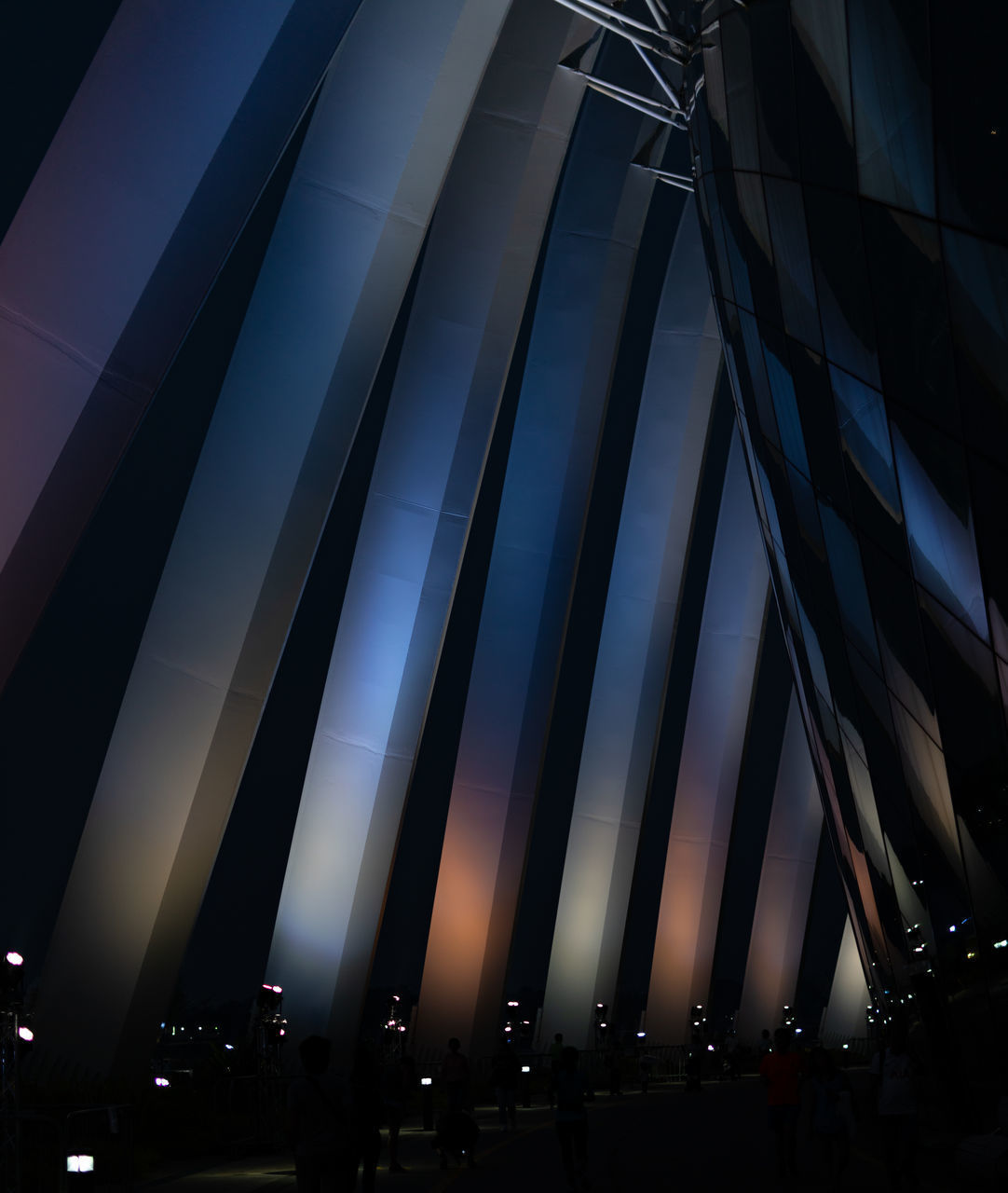 LOW ANGLE VIEW OF ILLUMINATED MODERN BUILDING AT NIGHT