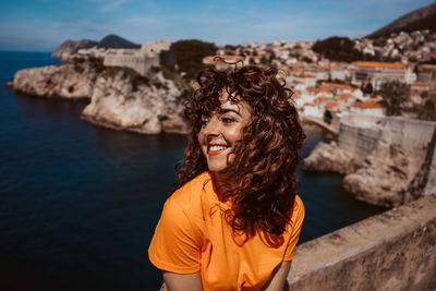 Portrait of young woman standing against sea