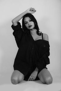 Portrait of young woman sitting against white background