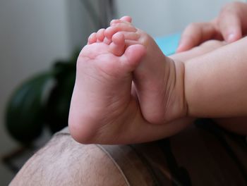 Cropped image of father carrying baby while sitting at home