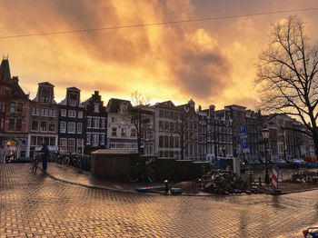 Buildings by street against sky at sunset