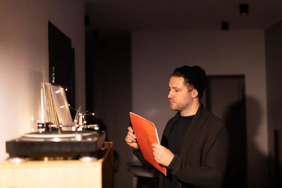 Young man holding camera while standing at home