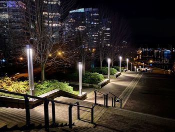 Illuminated park by buildings in city at night