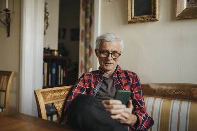 Senior man using smart phone at home