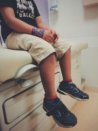 Low section of boy sitting on bed in clinic