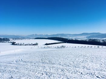 Scenic view of snow covered mountains against blue sky