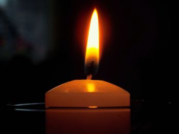 Close-up of lit candle in darkroom