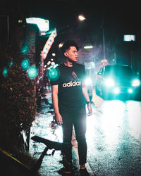 Full length of woman standing on illuminated street at night