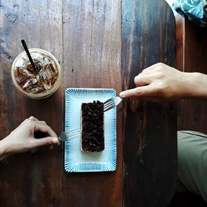 Cropped image of man and woman eating cake on table