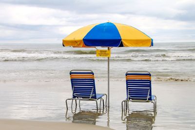 Deck chairs on beach against sky