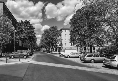 Cars on street by buildings against sky