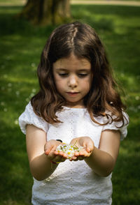 Portrait of a girl holding daisies in her palms on a summer day.