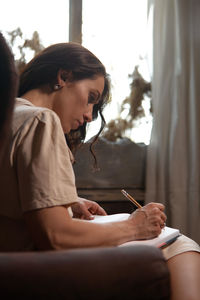 Woman writing in book at home