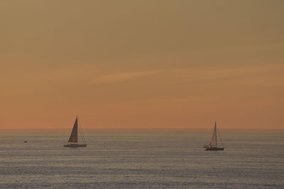 Sailboat sailing on sea against sky during sunset