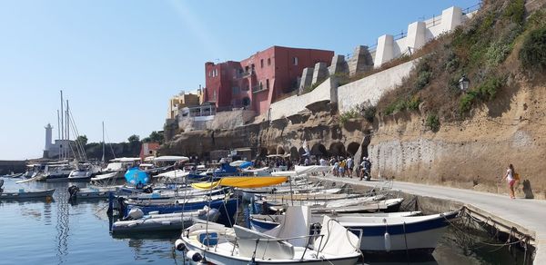 Sailboats moored at harbor against sky in city