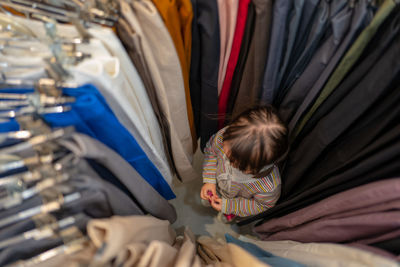 High angle view of girl standing amidst clothes rack