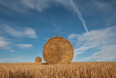 Hay bales on field against sky