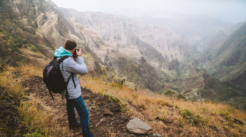 Rear view of man photographing while standing on mountain