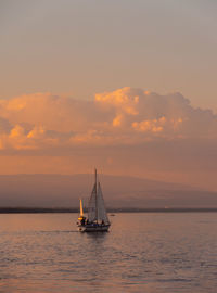 Sailboat sailing on sea against sky during sunset