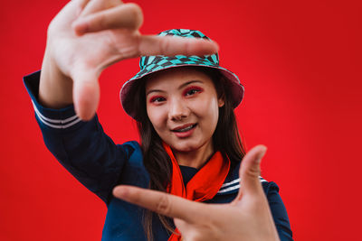 Portrait of young woman wearing hat against yellow background