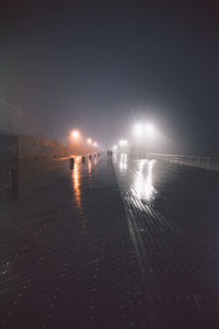 Illuminated street against sky at night