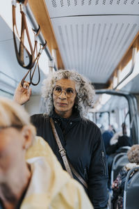 Contemplative female owner looking away while commuting through bus