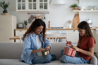 Female friends using phone while sitting at home