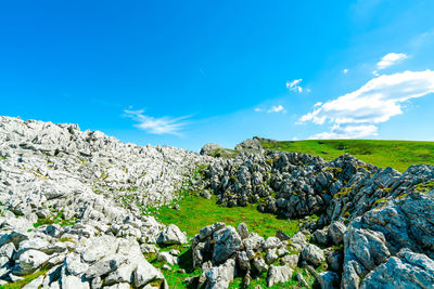 Landscape of green grass and rock hill in spring with beautiful blue sky and white clouds. 