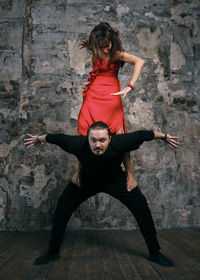 Full length of couple dancing against wall