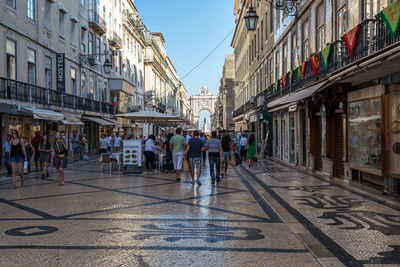 People walking on street amidst buildings in city