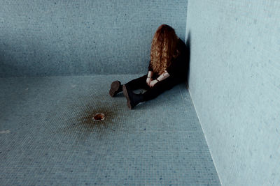 High angle view of sad woman sitting on tiled floor