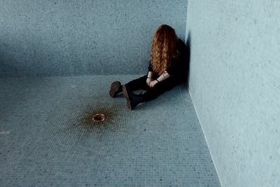 Side view of a woman sitting on floor in city