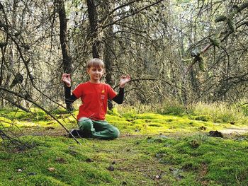 Full length of boy sitting on land against trees