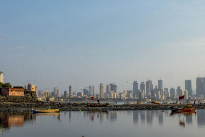 Lake and buildings in city against sky