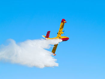 Low angle view of airplane flying against blue sky