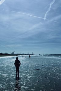 Rear view of man standing in sea against sky