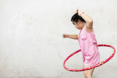 Full length of woman standing against pink wall