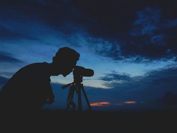 Silhouette of man taking picture of sunset