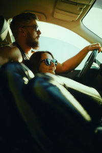 A woman and a man travel in a car in the summer.