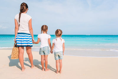 Friends standing on beach against sky