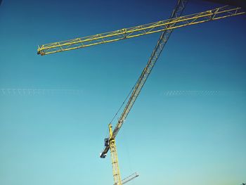 Low angle view of crane against clear blue sky