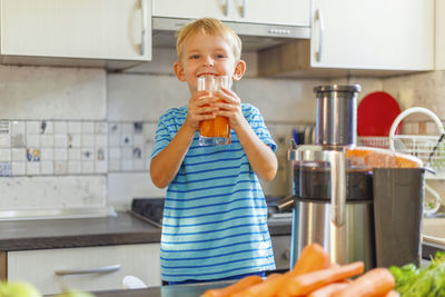 Portrait of young woman using mobile phone while standing in kitchen