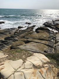 Scenic view of rocks on beach against sky